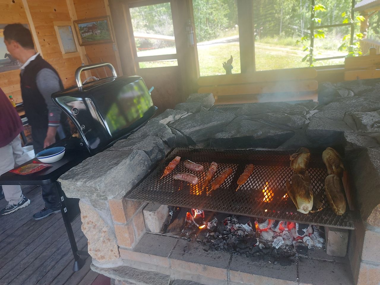 Community members grilling at a screened-in lakeside BBQ house at Lifechanyuan's Canada resort home, ...