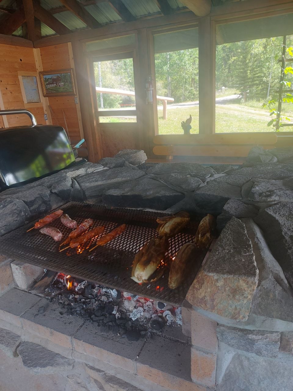 Community members grilling at a screened-in lakeside BBQ house at Lifechanyuan's Canada resort home, ...
