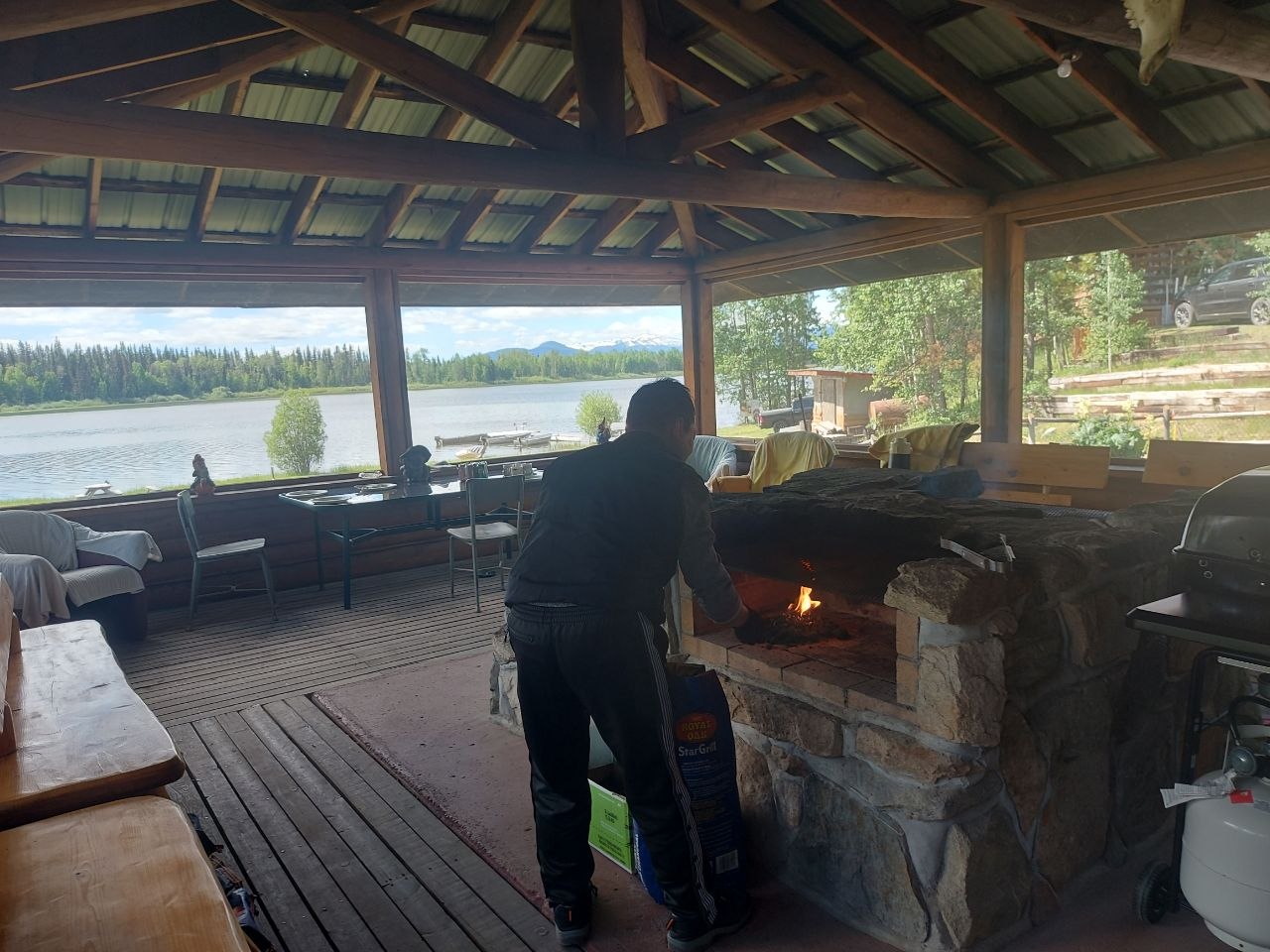 Community members grilling at a screened-in lakeside BBQ house at Lifechanyuan's Canada resort home, ...